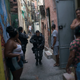 “A police officer patrols among residents during an operation against drug traffickers at the ‘pacified’ Jacarezinho slum in Rio de Janeiro, Brazil.”